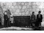 Czwórka uczniów i nauczyciel obok tablicy z napisem Campulung-Muscel Polska Szkoła Powszechna w Rumunii.