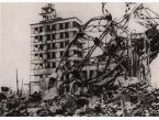 Zniszczenia spowodowane wybuchem bomby atomowej nad Hiroshimą - poskręcana masa stalowej konstrukcji na pierwszym planie, w oddali widoczny jest zniszczony budynek.